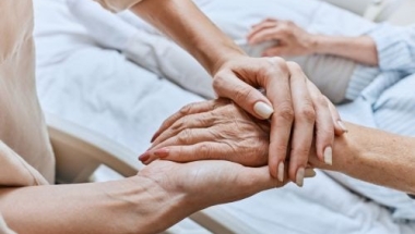 A nurse holds the hand of a hospice patient.